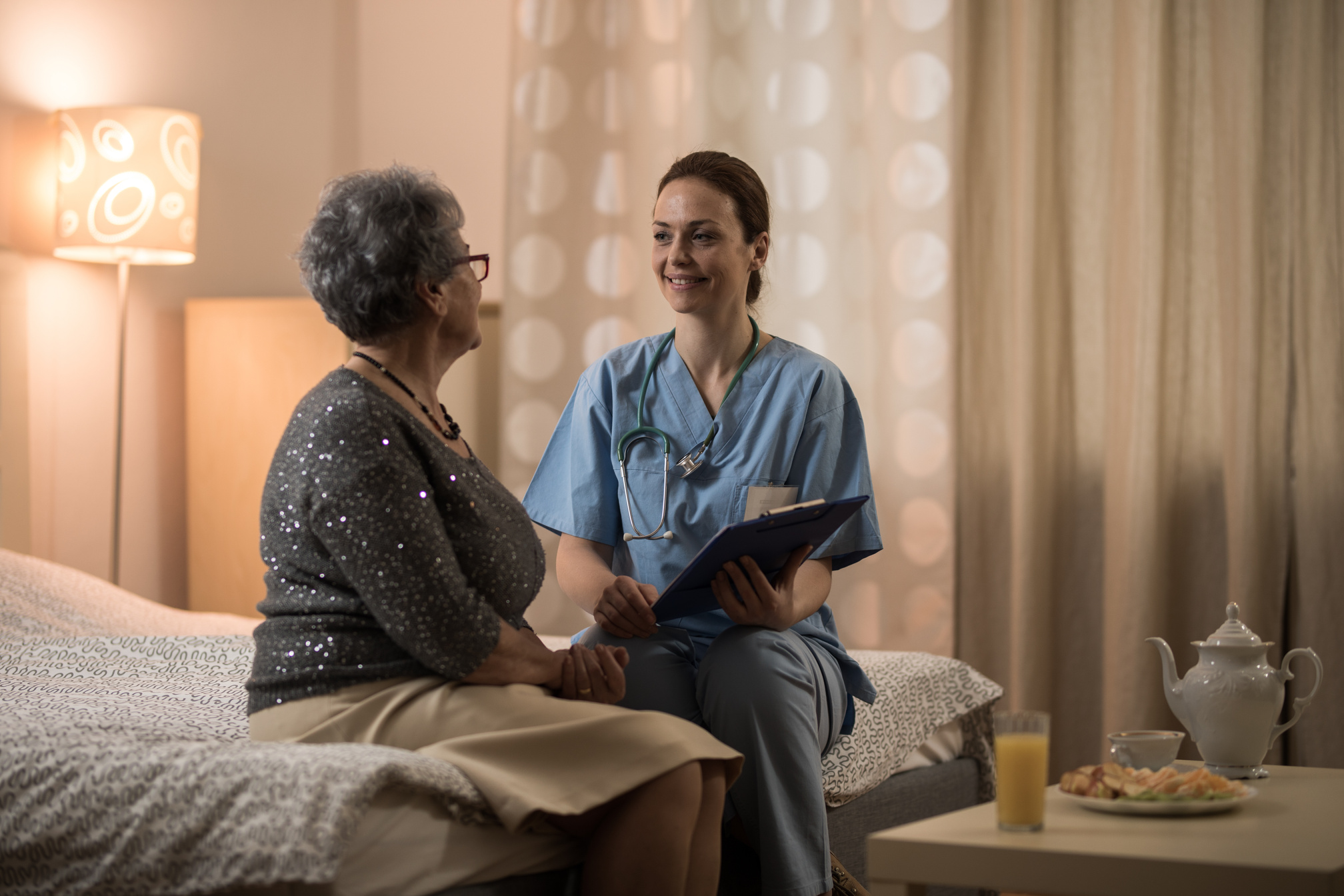 Homecare nurse talking with senior women at home in bedroom